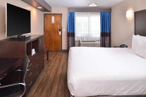 a hotel room with a bed and a flat screen tv at Tarzana Inn in Tarzana