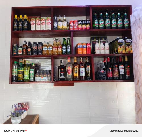een plank vol met allerlei soorten drankjes bij UniZone Guest House in Sunyani