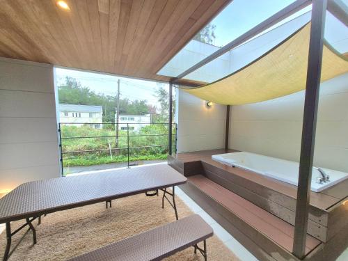 a room with a tub and a bench and a large window at Villa YUKUI in Onna