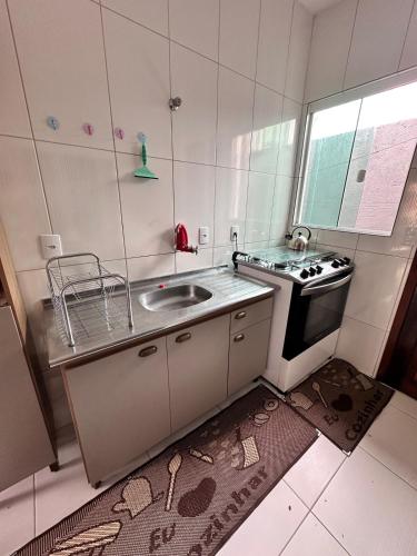 a small kitchen with a sink and a stove at Refúgio do Churrasco in Matinhos