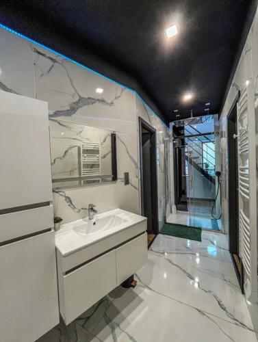 a white bathroom with a sink and a mirror at Loft Moderne Avec Jacuzzi Roft top Le B in Baccarat