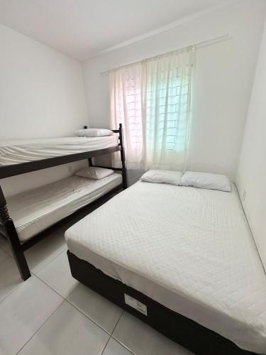a bedroom with two bunk beds and a window at Refúgio do Churrasco in Matinhos