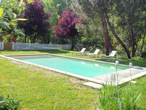 a swimming pool in a yard with two chairs and a fence at Chambres d'Hôtes Le Grand Chaleat in Éclassan