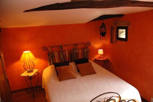 a bedroom with a bed with orange walls and two lamps at Chambres d'Hôtes Le Grand Chaleat in Éclassan
