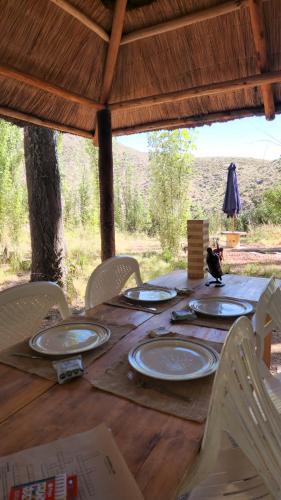 einem Holztisch mit Stühlen und Tellern darauf in der Unterkunft Cálida casa de montaña in Potrerillos