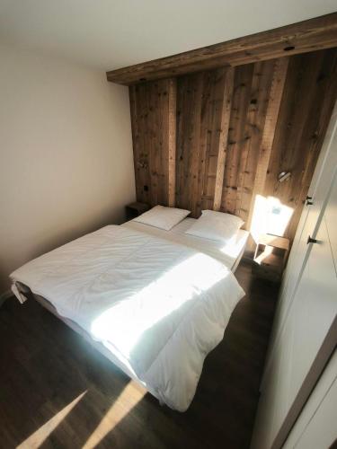 a bedroom with a white bed with a wooden wall at Temples Du Soleil Tikal Appartements VTI in Val Thorens