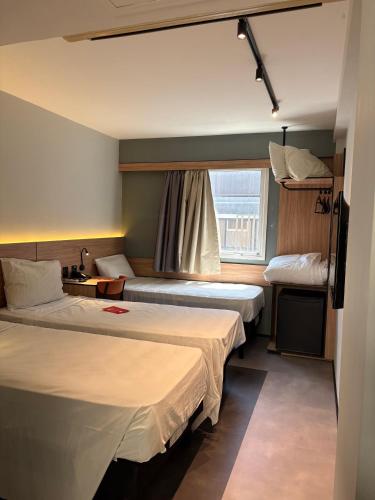 a hotel room with two beds and a window at Ibis Joao Pessoa Praia in João Pessoa