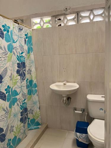 a bathroom with a sink and a toilet and a shower curtain at Villa Conchita - Piscina Privada y BBQ in Carmen de Apicalá