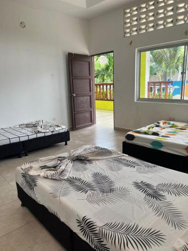 a room with two beds and a door with a window at Villa Conchita - Piscina Privada y BBQ in Carmen de Apicalá