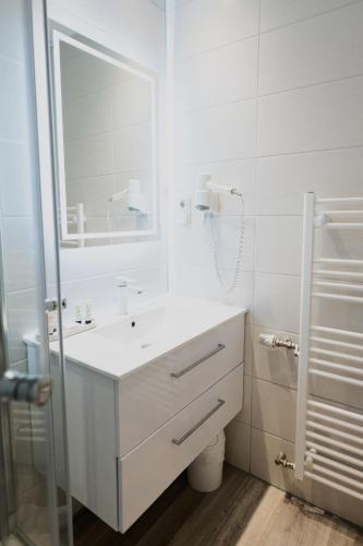 a white bathroom with a sink and a mirror at Hotel Landhaus Dierkow in Rostock