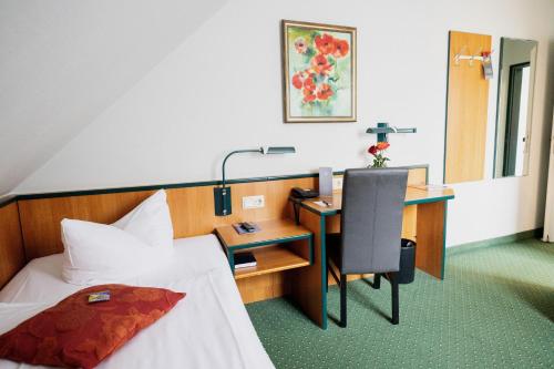 een hotelkamer met een bed en een bureau met een bureau bij Hotel Landhaus Dierkow in Rostock