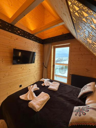 a bedroom with a bed with towels on it at Horizont House - domki z prywatnymi baliami oraz ogólnodostępną sauną - IZBY PODHALAŃSKIE in Dursztyn