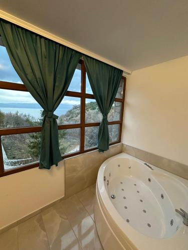 a bathroom with a tub and a large window at Apartments BRAVO in Ohrid