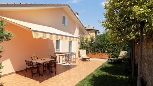 een patio met een tafel en stoelen naast een huis bij MillyHolidays - Apartment Sunflower - Center - Nearby Beach - Private Garden - Spa Pool in Bardolino