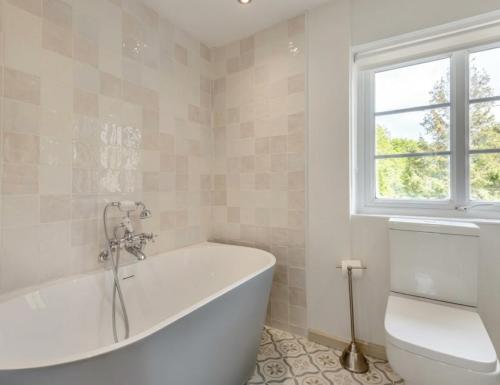 a white bath tub in a bathroom with a window at Fig Tree Cottage - Corfe Castle in Corfe Castle