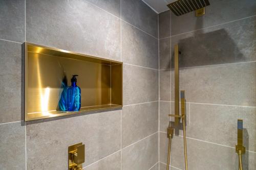 a bathroom with a shower with a blue bottle on a shelf at Daresbury Park Hotel in Daresbury