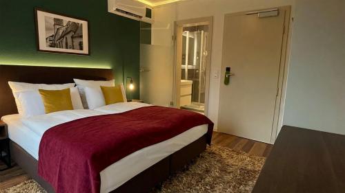 een slaapkamer met een groot bed met een rode deken bij Das Mühlentor Hotel in Bad Kreuznach