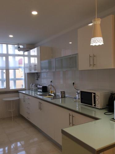 a kitchen with white cabinets and a microwave at 4U Lisbon IV Guesthouse Airport in Lisbon
