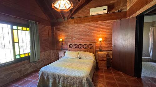 a bedroom with a bed and a brick wall at Encantos del Bosque in Colón
