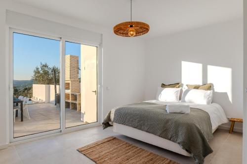 a white bedroom with a bed and a balcony at Green House Zêzere in Souto