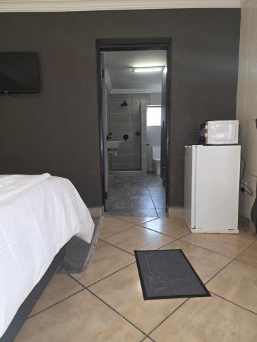 a bedroom with a bed and a bathroom with a refrigerator at The Good Samaritan 4 in eMalahleni