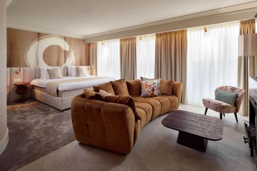 een woonkamer met een bank en een bed in een hotelkamer bij Van der Valk Palace Hotel Noordwijk in Noordwijk aan Zee