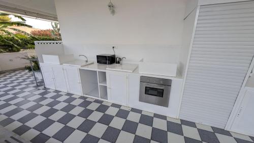 a kitchen with white cabinets and a checkered floor at Casa vacanze Lu Salentu in Torre Lapillo