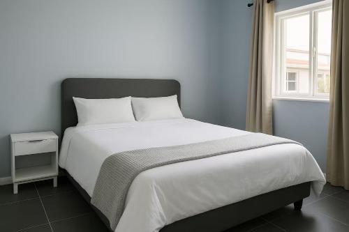 a bedroom with a large white bed with a window at Evangeline House in Cape Town