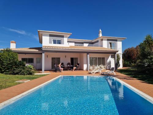 a villa with a swimming pool in front of a house at Villa Montanha, 4 Bedroom Villa, with swimming pool, loungers and alfresco dining, 10 min walk to the beautiful Praia da Luz Beach, Shops, Bars and Restaurants! in Luz