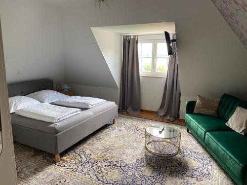 a living room with a bed and a green couch at Reetdachhaus Windblume - super gemütlich in Zinnowitz