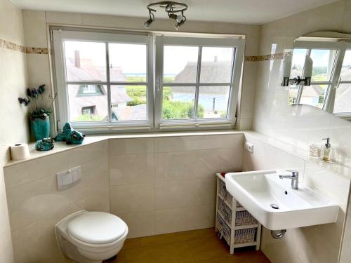a bathroom with a toilet and a sink and two windows at Reetdachhaus Windblume - super gemütlich in Zinnowitz
