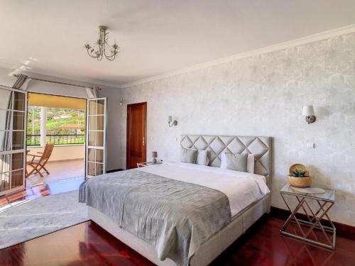 a bedroom with a large bed and a balcony at Villa Baradaye by Atlantic Holiday in Estreito da Calheta