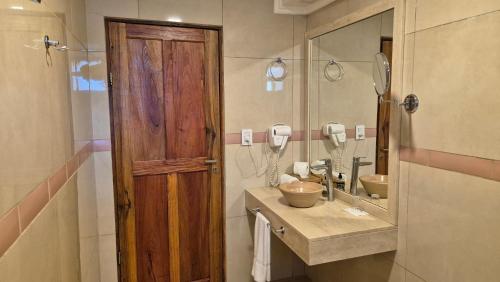 een badkamer met een houten deur en een wastafel bij El Pueblito Iguazú in Puerto Iguazú