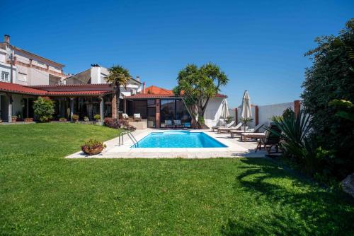 a backyard with a swimming pool and a house at Villa dos Corcéis in Esposende
