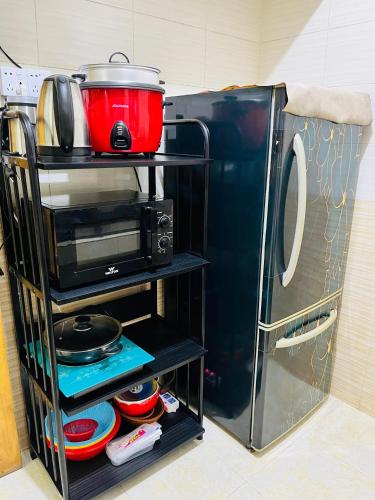 un supporto con un forno a microonde accanto a un frigorifero di Paradise Suite's a Dhaka