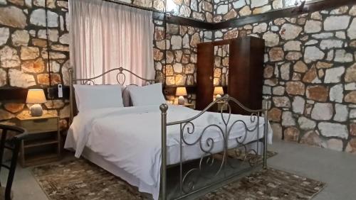 a bedroom with a bed and a stone wall at Leo Villas in Florina