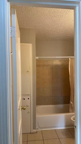 a bathroom with a white tub and a shower at Only 25 dollars-Man's bed in a room in Texas City