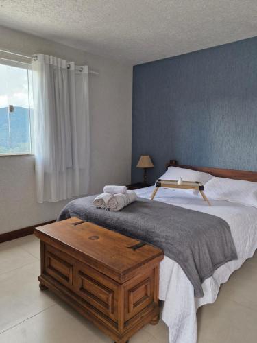 a bedroom with a large bed with a wooden table at Encantos do vale Teresópolis in Teresópolis