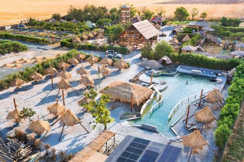 een luchtzicht op een resort met een zwembad en rieten parasols bij La Colibe, cătun arhaic ecologic in Constanţa