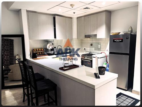 a kitchen with white cabinets and a black refrigerator at Ark Living Stay in Yas Island in Yas Island