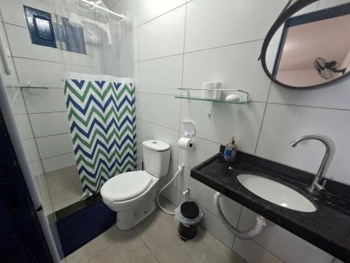 a bathroom with a toilet and a sink and a mirror at Casa da Janelas Azuis Praia Azul in Pitimbu