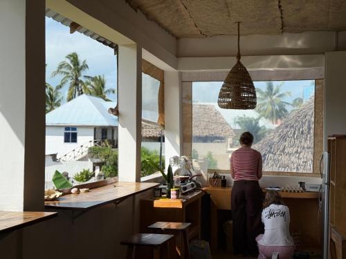 a woman standing in a kitchen looking out the window at Mlango Paje House II in Paje