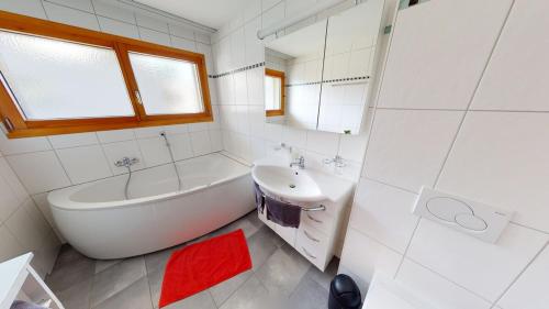 a white bathroom with a tub and a sink at Bijou in Mitten von Naters in Naters