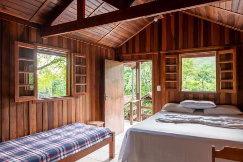 a bedroom with a bed and windows in a room at Pousada Ypê das Montanhas in Monte Alegre do Sul