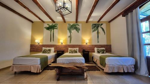 twee bedden in een kamer met palmbomen aan de muur bij El Pueblito Iguazú in Puerto Iguazú