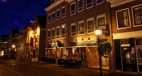 a building with a cafe on a street at night at Hampshire Hotel Petit Nord in Hoorn