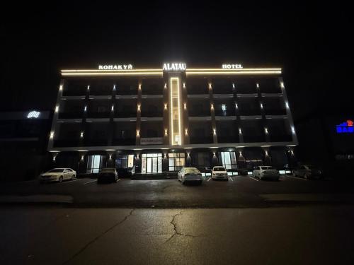 a building with cars parked in a parking lot at night at Alatau hotel in Shymkent