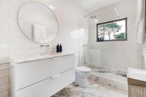 a white bathroom with a toilet and a mirror at Chalet da Azenhas in Colares