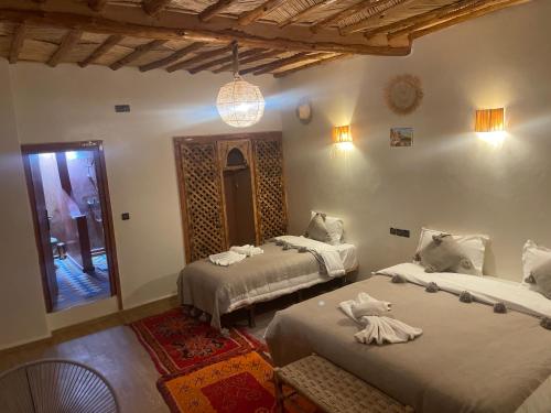 a bedroom with two beds and a chandelier at Hotel Soleil Blue in Boumalne Dades