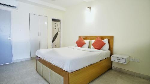 a bedroom with a bed with white sheets and red pillows at Ashu Villa in New Delhi
